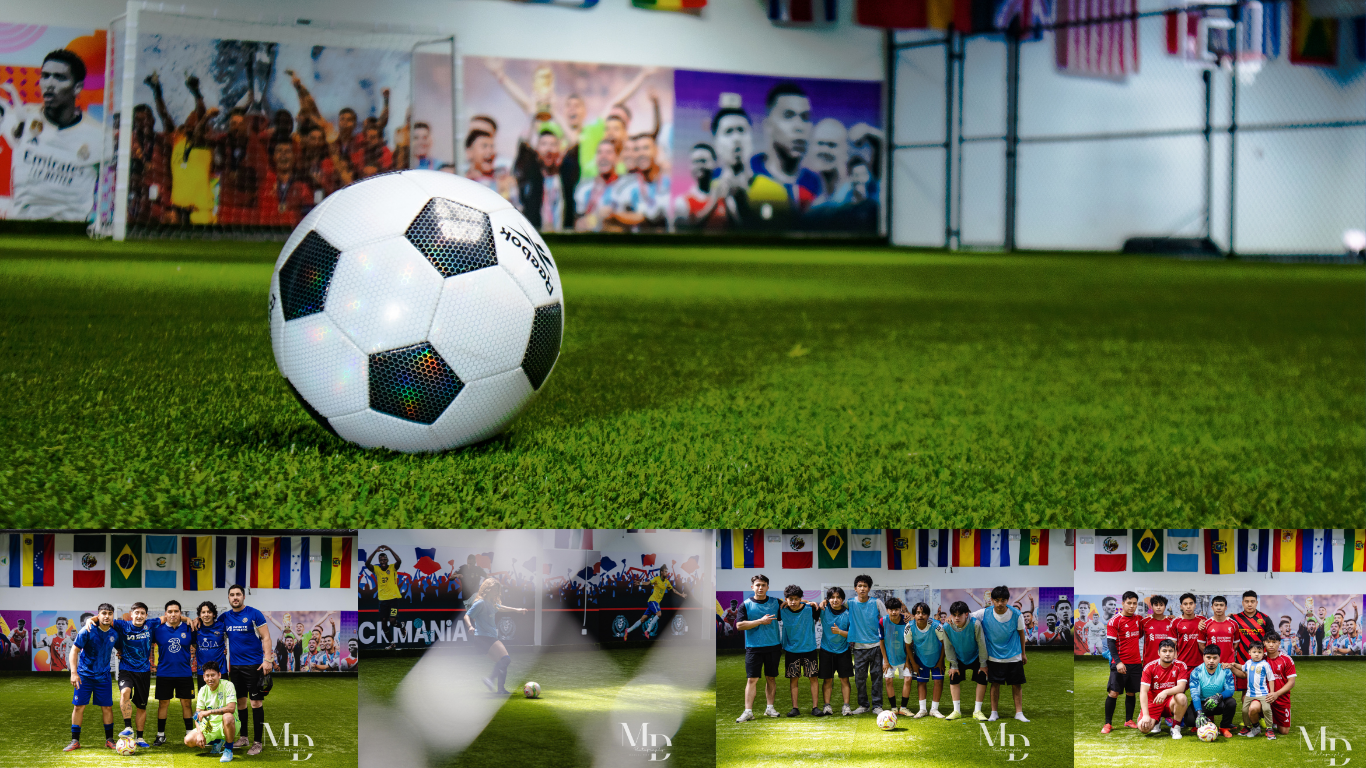 Soccer ball on indoor futsal field with colorful World Cup murals, international flags, and teams of players at Kickmania